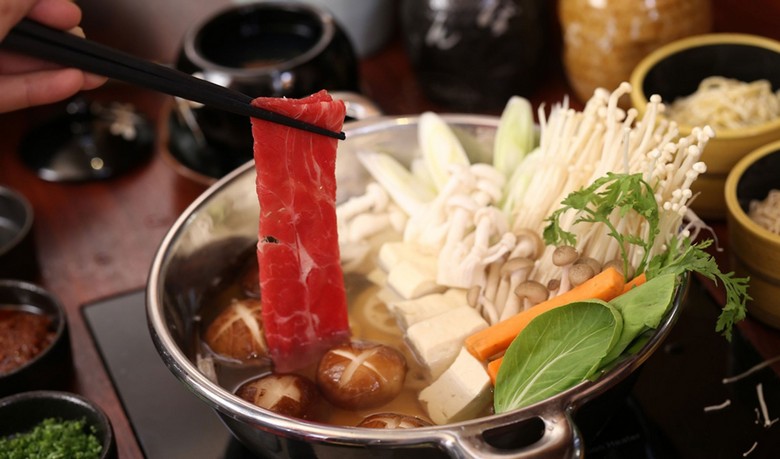 Lát thịt bò mỏng được nhúng trong nồi nước dùng shabu-shabu trong