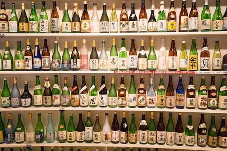 Vài chai sake Nhật xếp trên kệ gỗ trong cửa hàng rượu