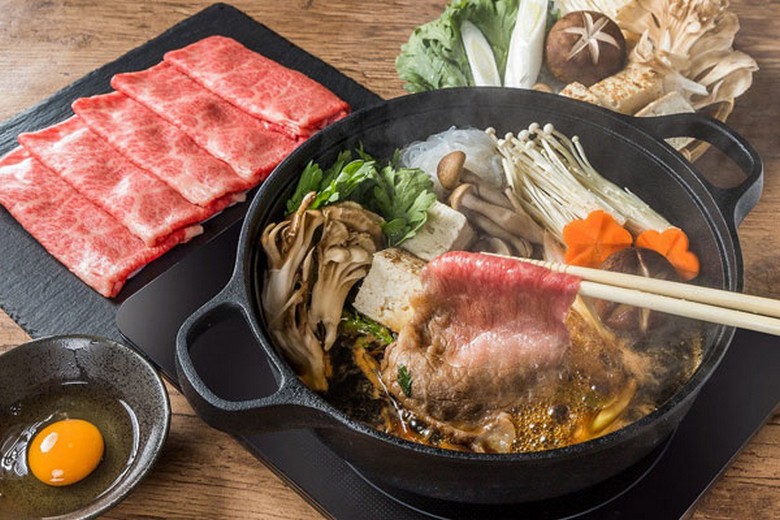 Nồi sukiyaki với thịt bò vân mỡ, đậu phụ và rau, bên cạnh chén trứng sống